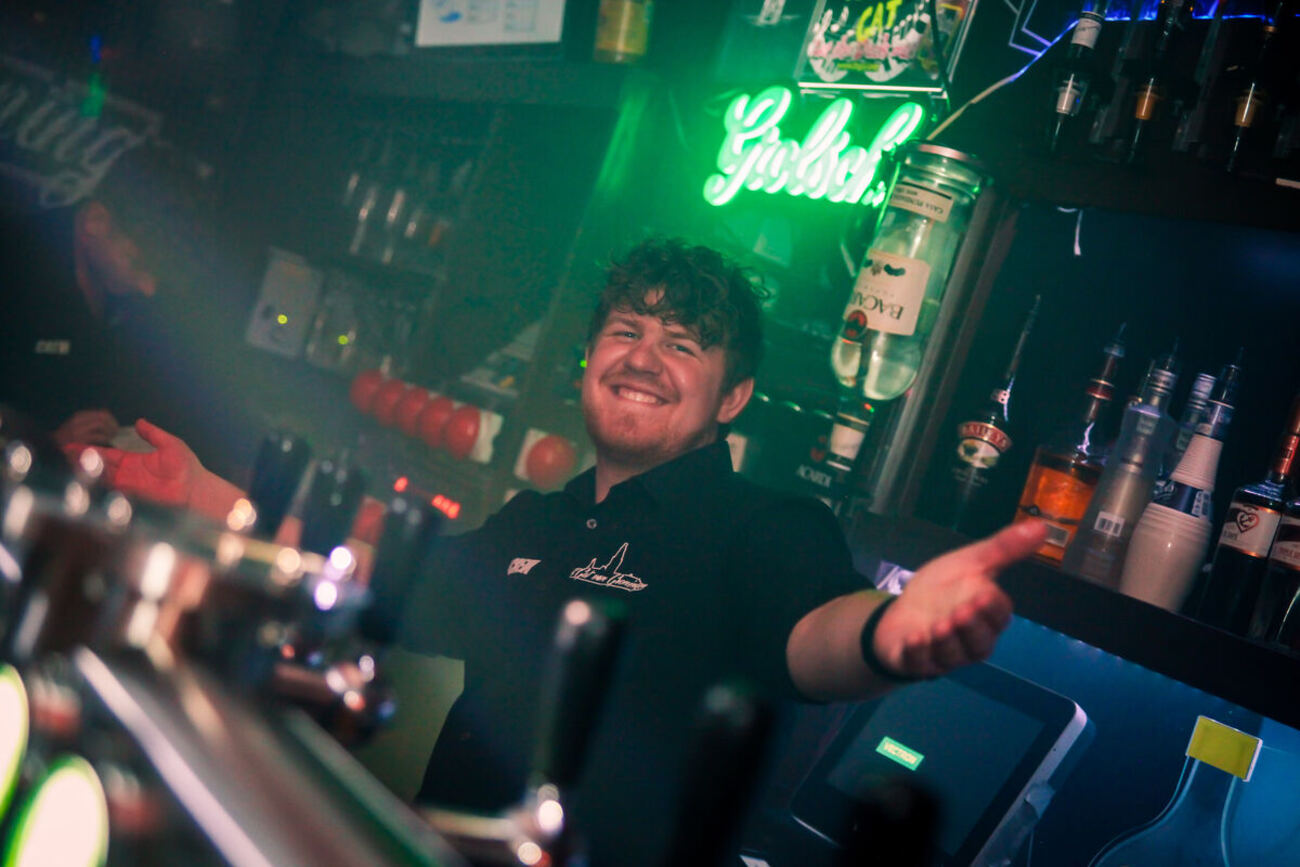 Bartender achter de tap van 't Gat van Groningen onder groen neonlicht