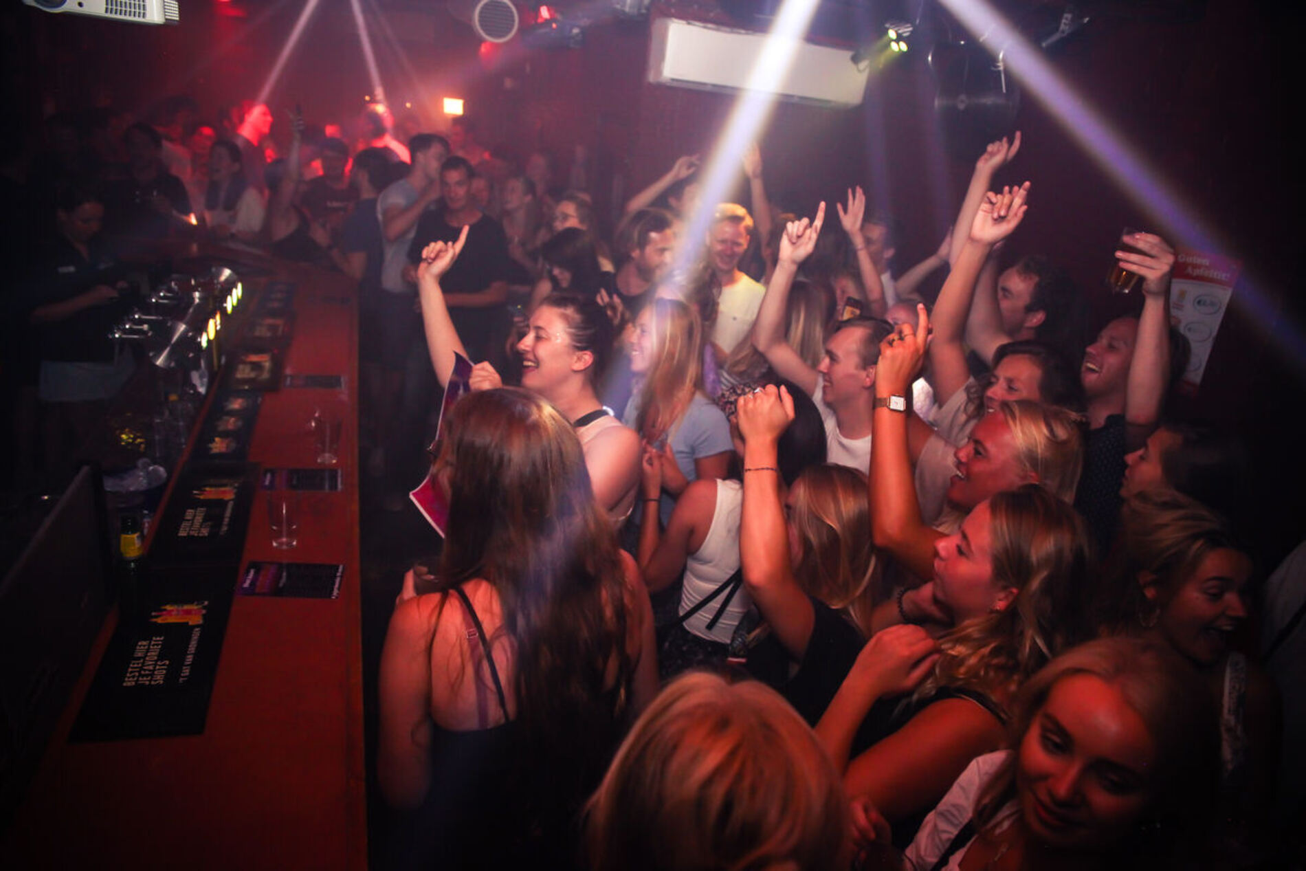 Feestende mensen met de handen omhoog in 't Gat van Groningen onder gekleurd lichteffect